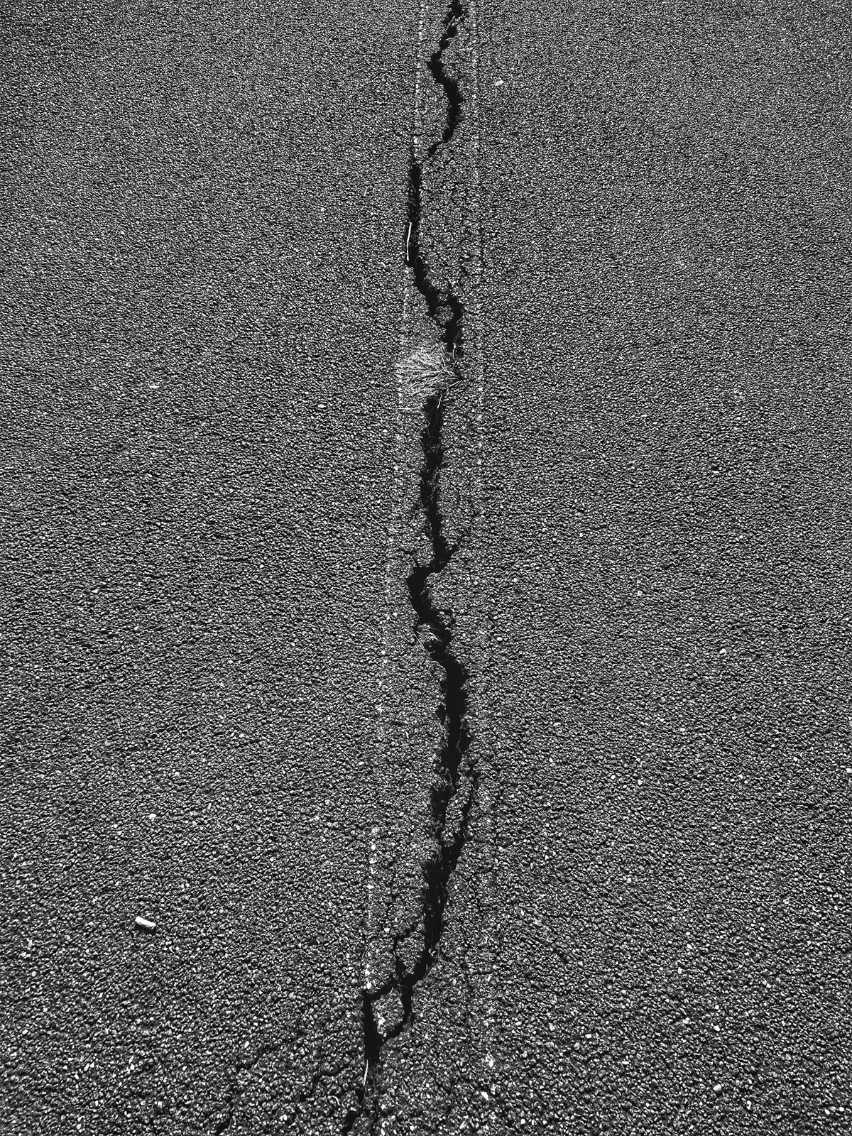 Close view of a long crack in an asphalt surface.