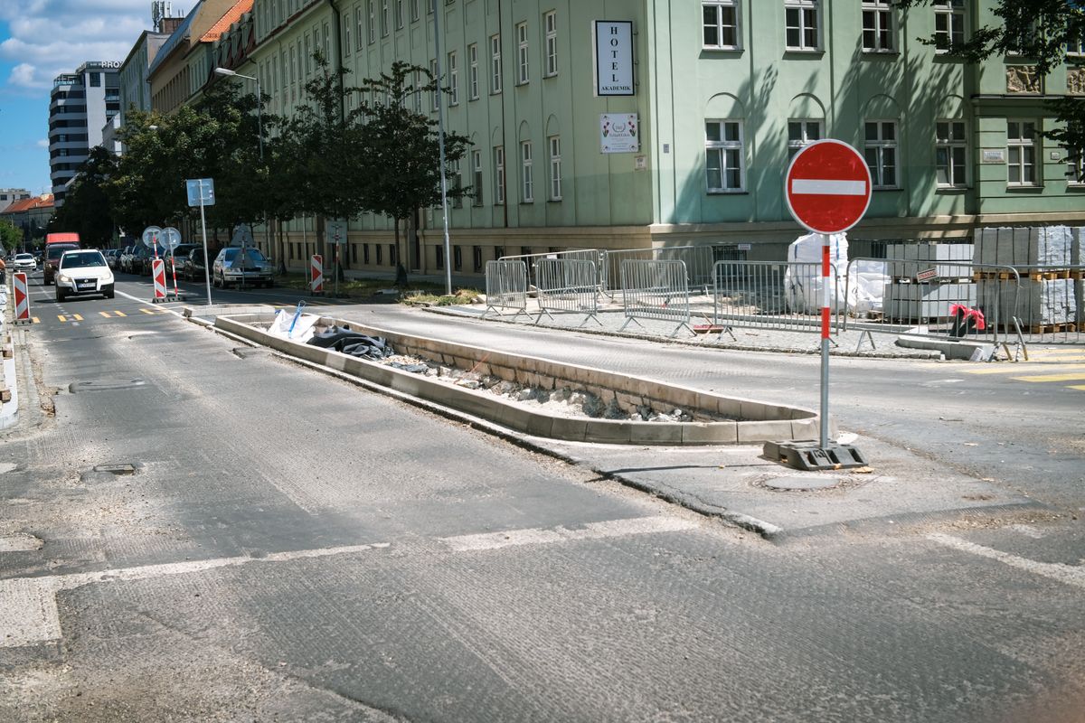 Urban road work with exposed pavement edges and traffic barriers.