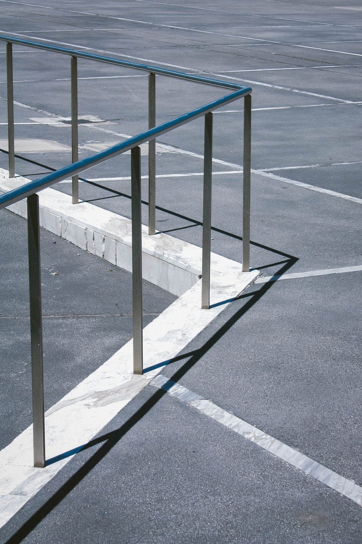 Metal handrails beside a concrete walkway and marked asphalt.