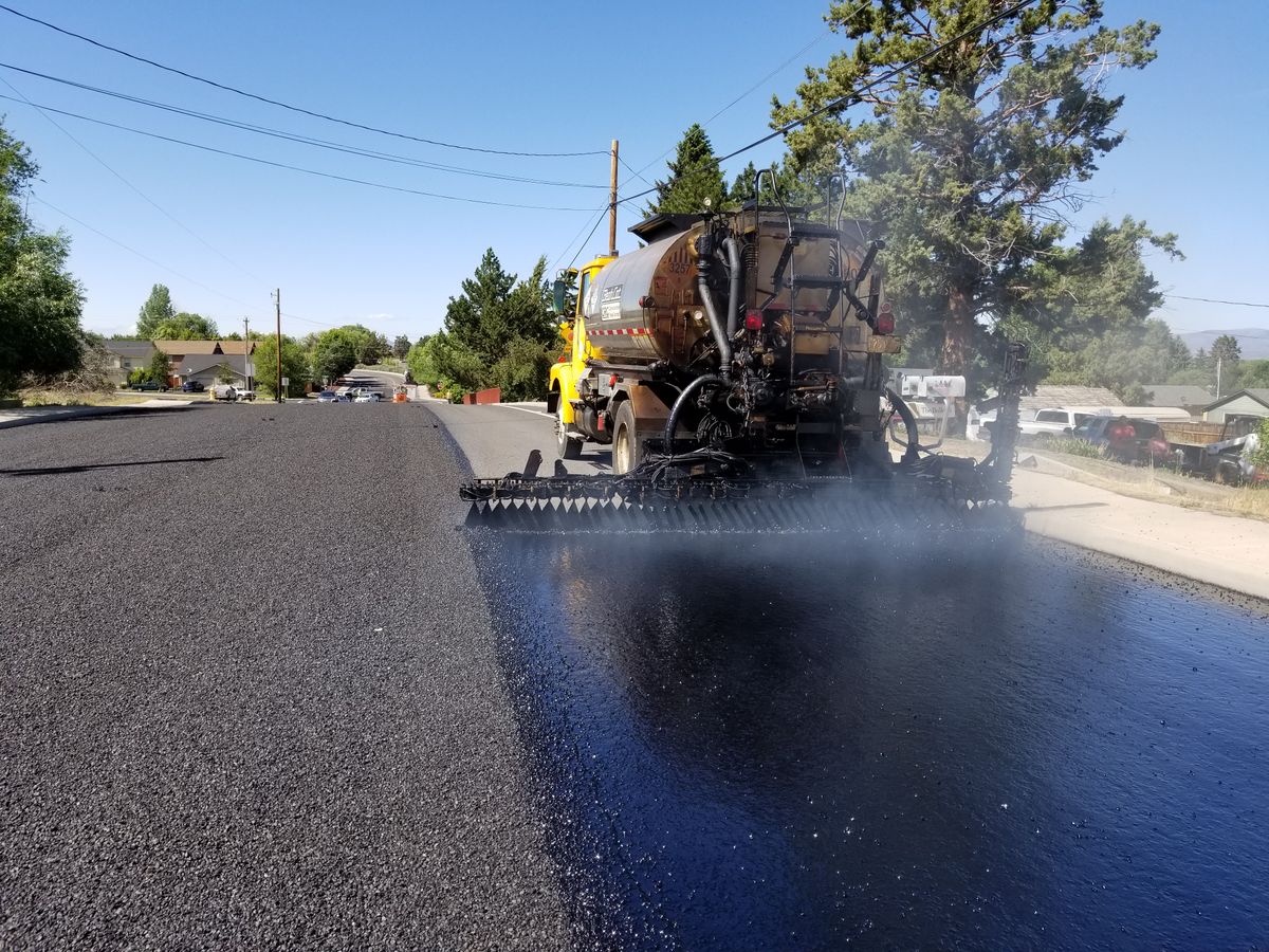 Asphalt paving machine laying a dark road surface.