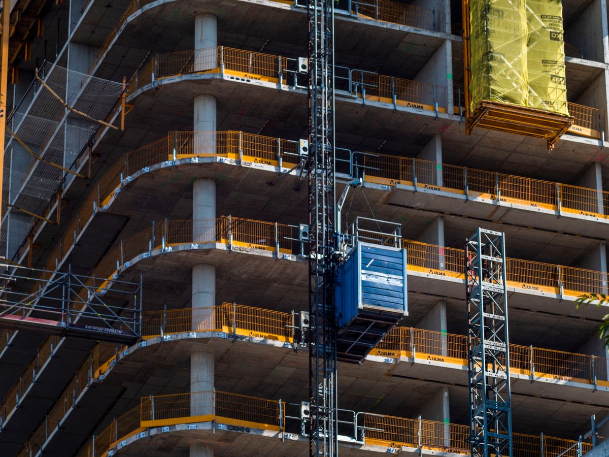 Multi-storey concrete building under construction with safety railings.