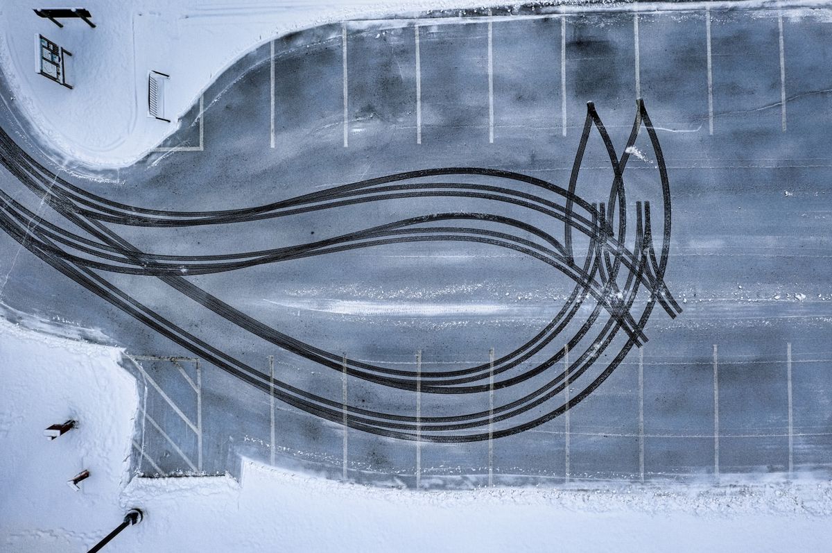 Aerial view of tire tracks across a snow-covered parking lot.