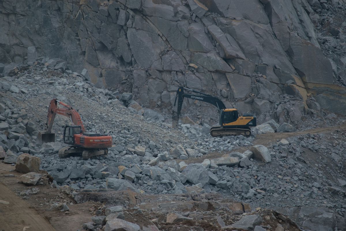Excavators working among rock and aggregate on a construction site.
