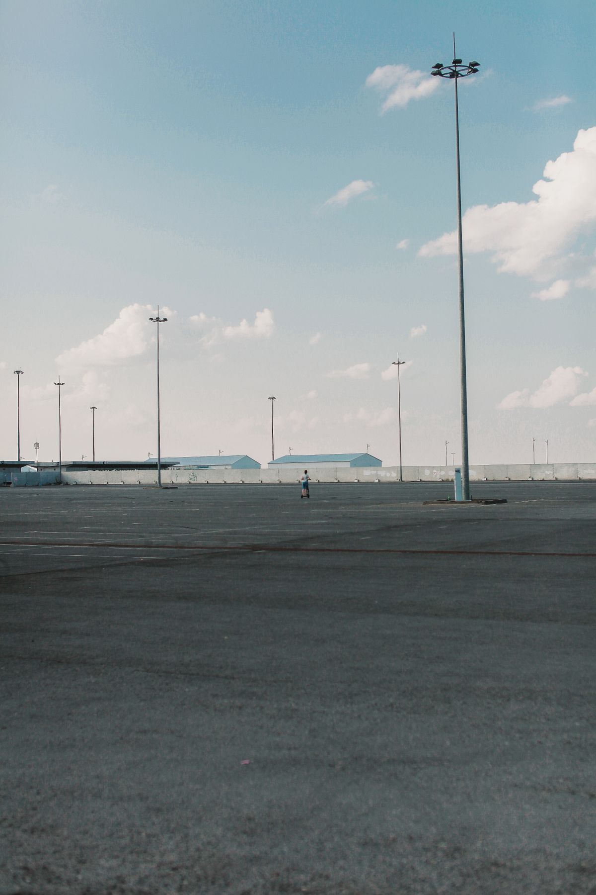 Open paved parking area with tall light poles.