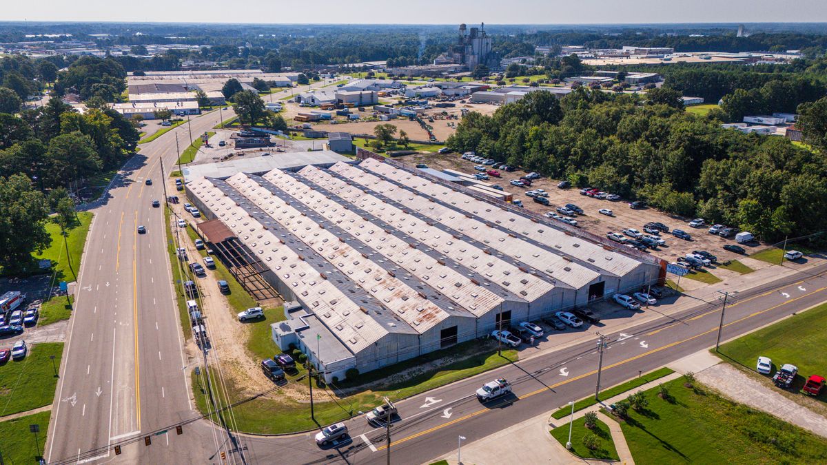 Aerial view of a large commercial building, access roads and parking areas.