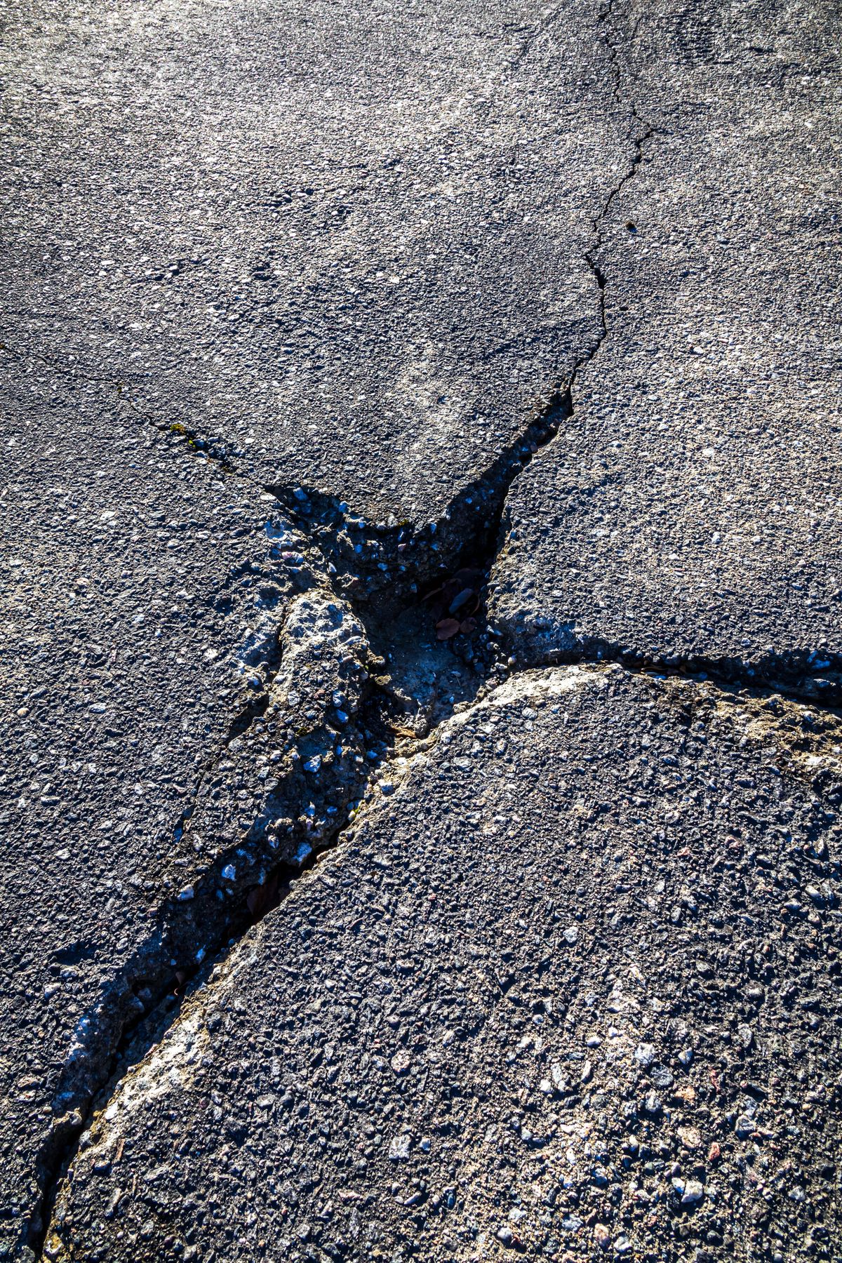 Broken asphalt around an open cavity and branching cracks.