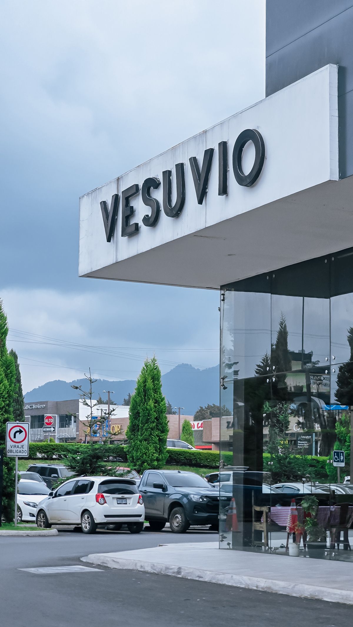 Restaurant frontage beside parked cars and a paved access area.
