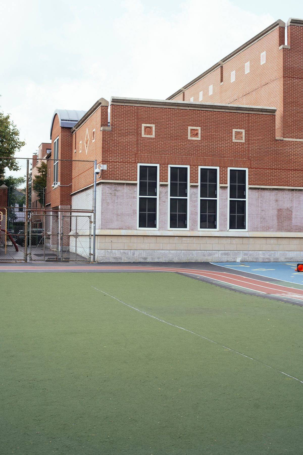 Brick school building beside an outdoor sports area.