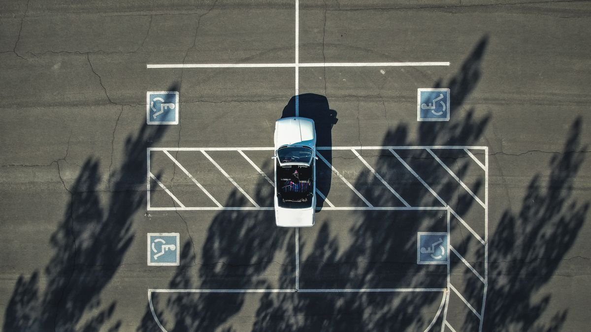 Overhead view of marked accessible parking spaces and a parked car.