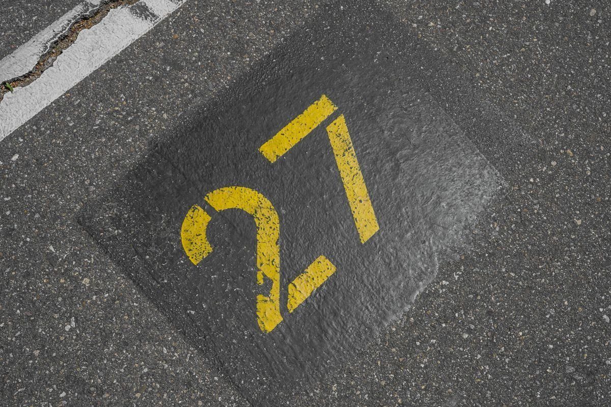 Yellow number painted on a textured asphalt parking space.
