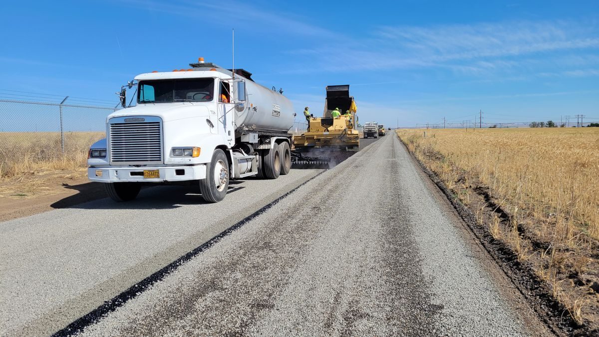 Tanker truck and road machinery working along a rural lane.