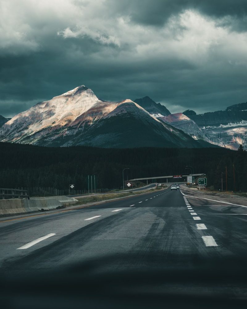 Marked highway pavement leading toward distant mountains.