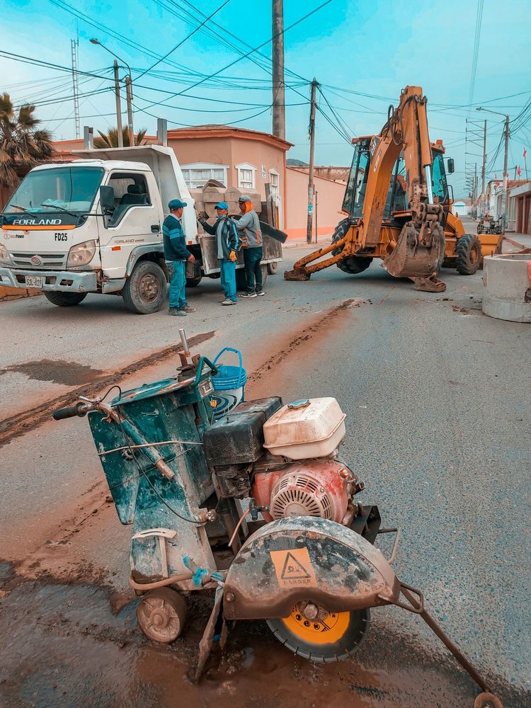Pavement cutting equipment beside a truck and excavator at a street work site.