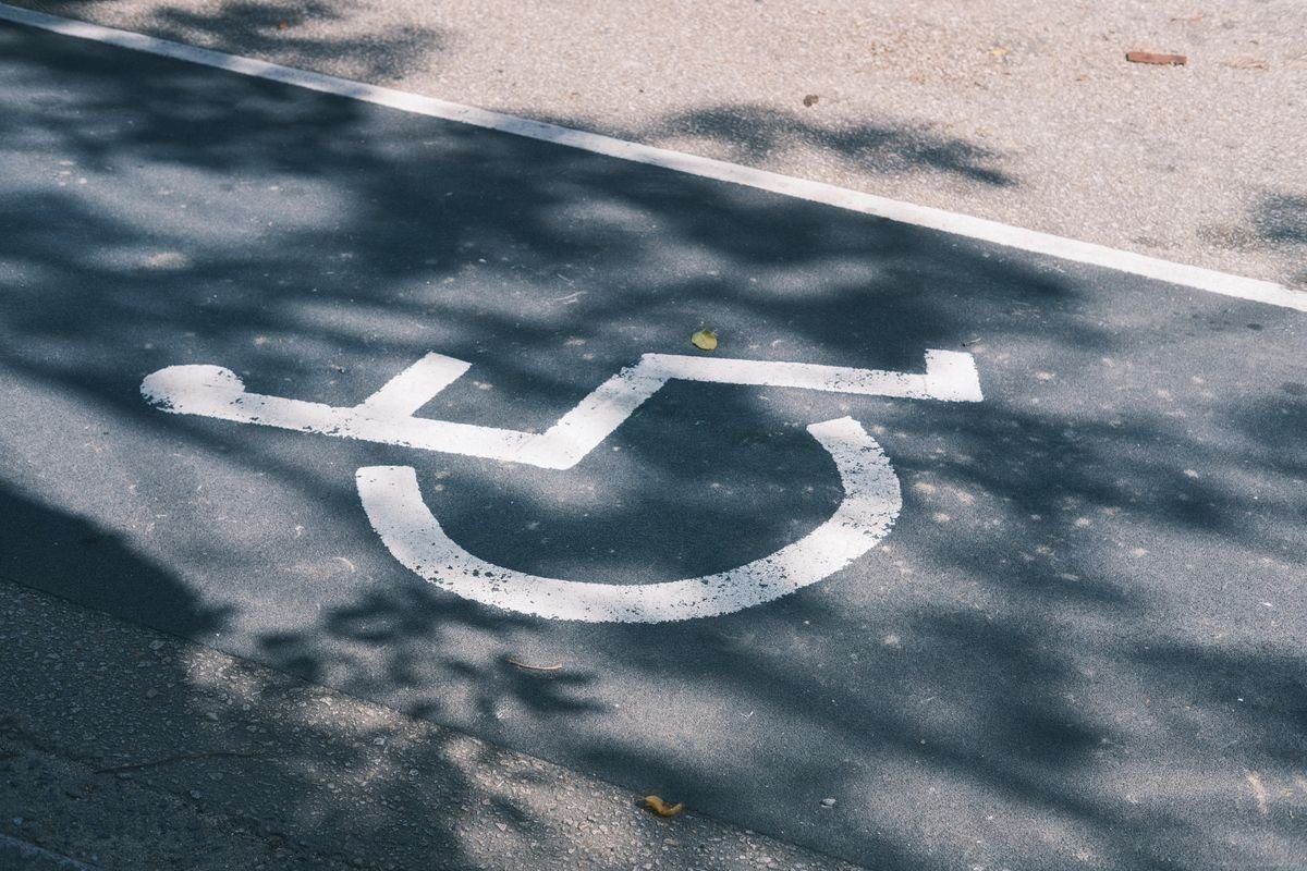 White accessible parking symbol on sunlit asphalt.