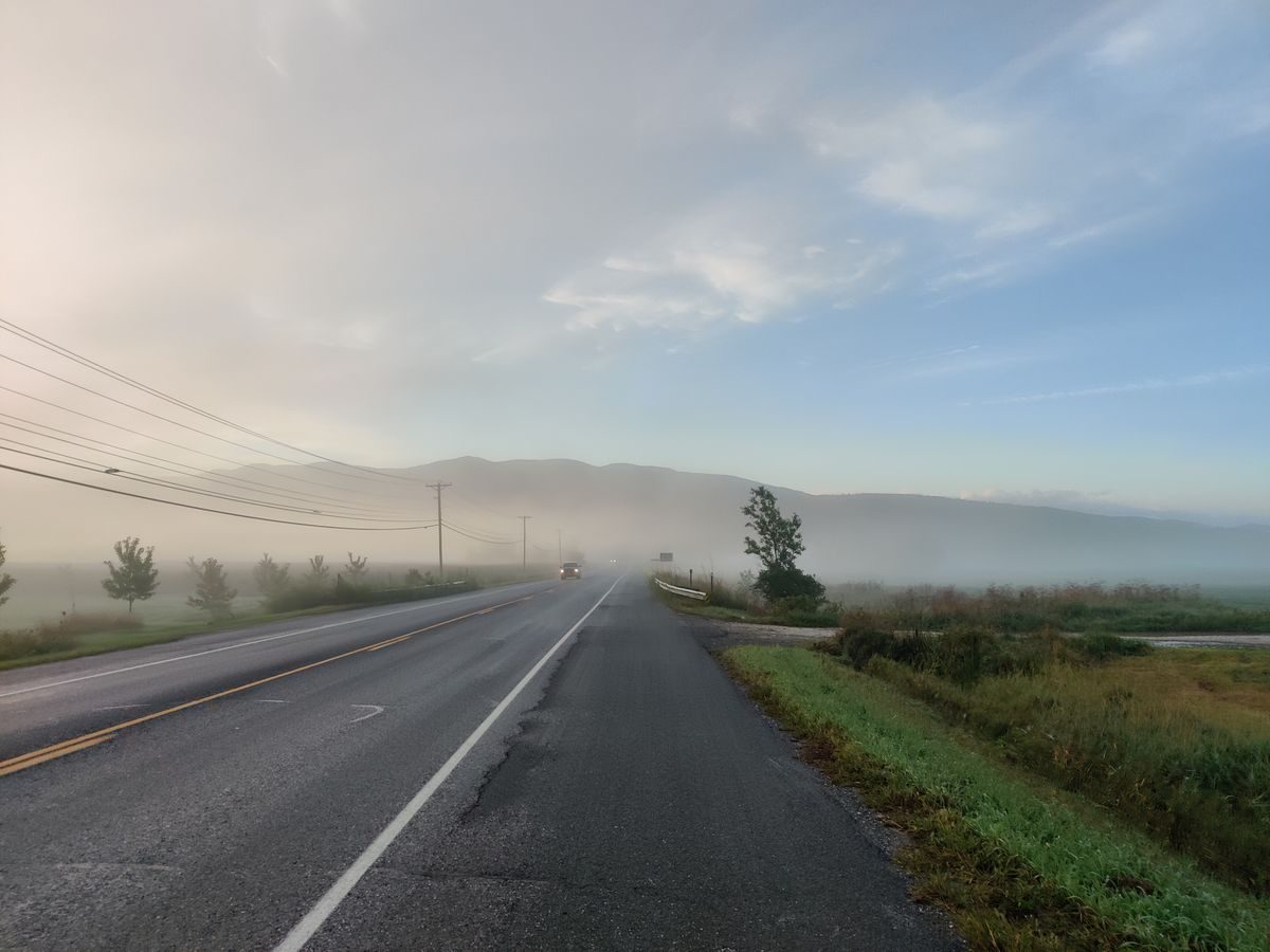 Paved roadway with marked shoulders in morning mist.