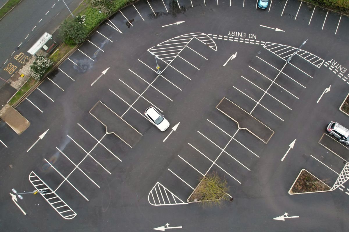 Aerial view of asphalt parking bays and directional markings.