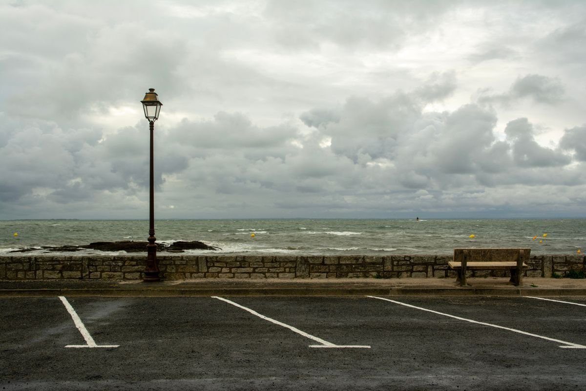 Marked asphalt parking spaces beside a waterfront wall.