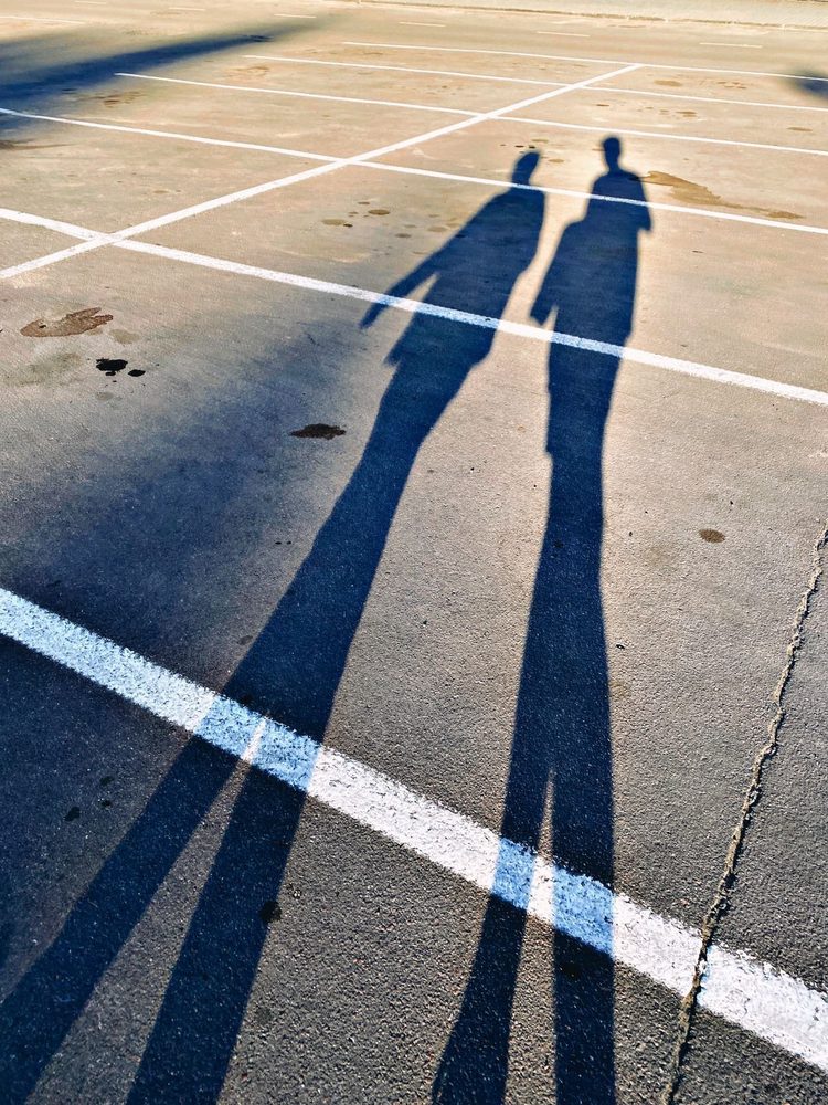 Long shadows crossing white parking lines on asphalt.