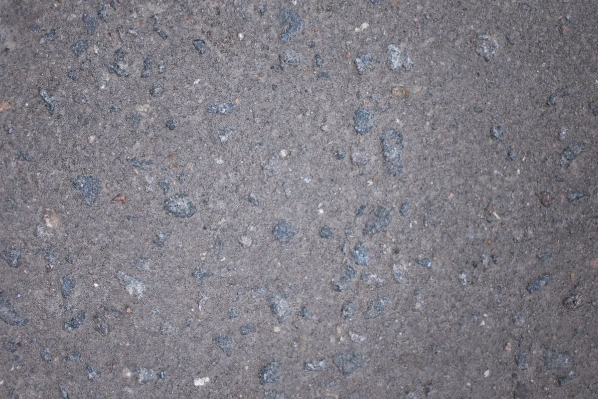 Grey pavement surface with visible stone aggregate.