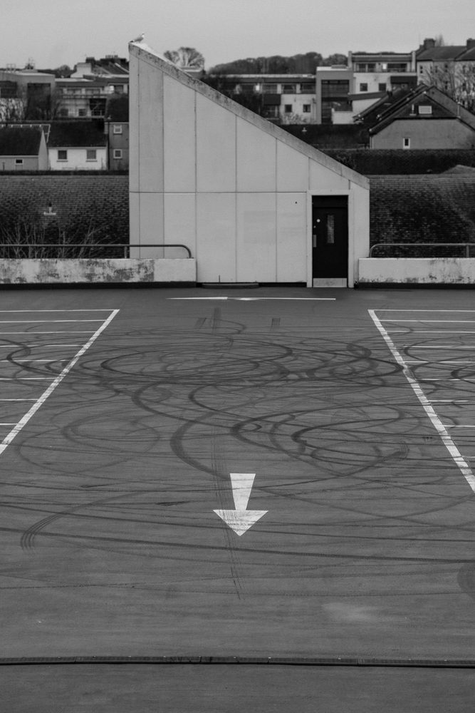 Directional arrow and tire marks on an asphalt parking surface.