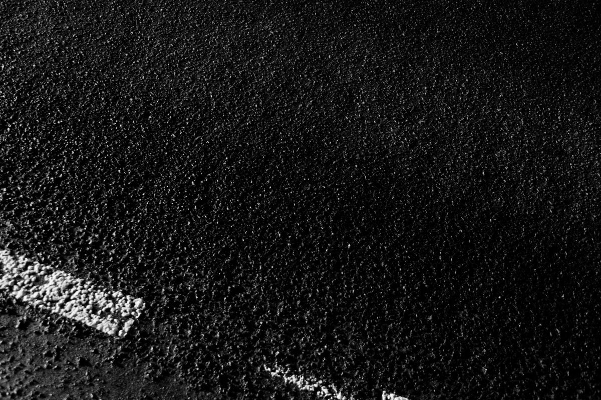 White road marking on dark textured asphalt.