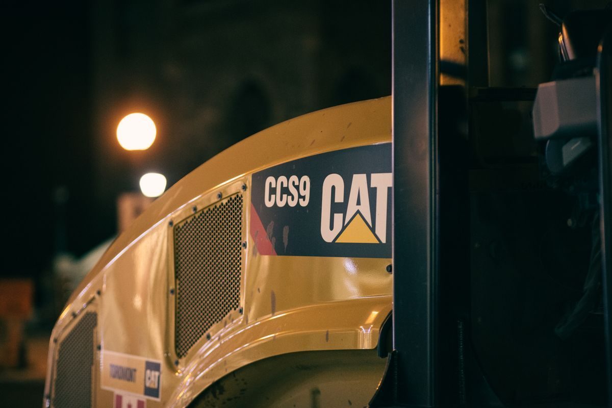 Close view of yellow road compaction equipment at night.