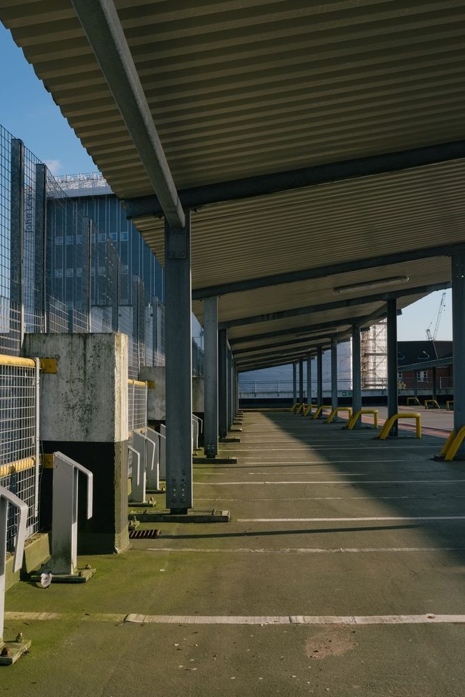 Covered parking spaces beside a metal fence.