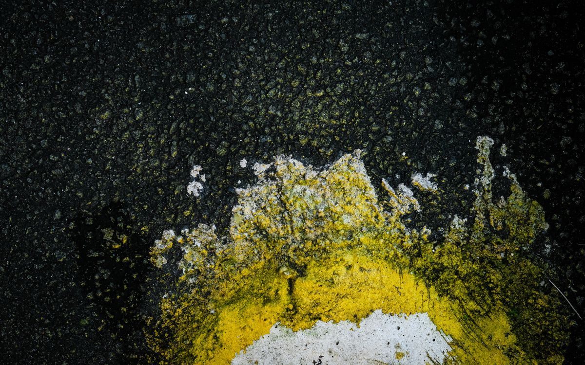 Worn yellow paint on a dark textured asphalt surface.