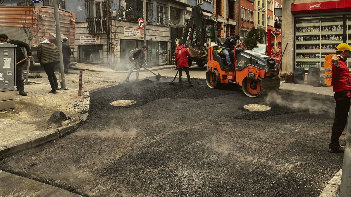 Road crew and compact rollers resurfacing an urban street.