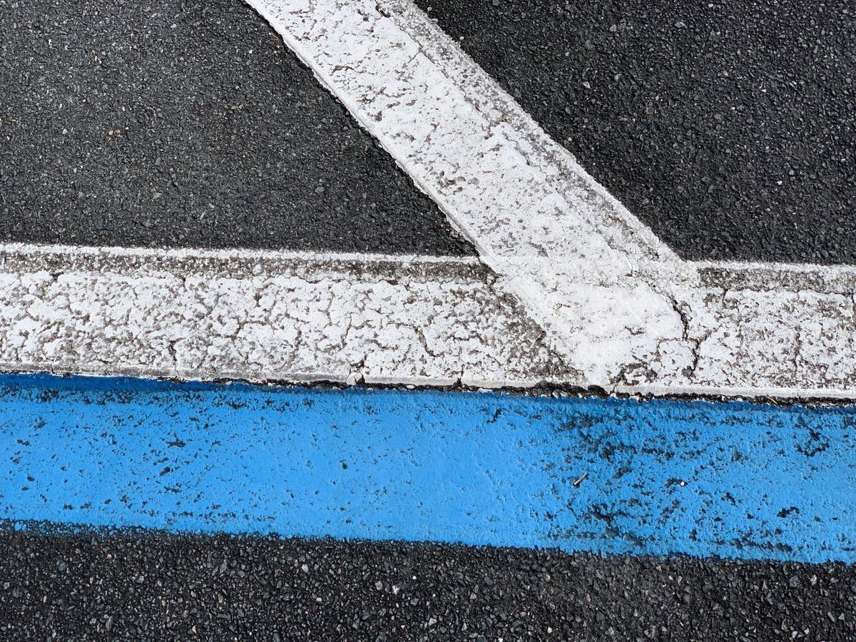 Blue and white painted lines on textured asphalt.