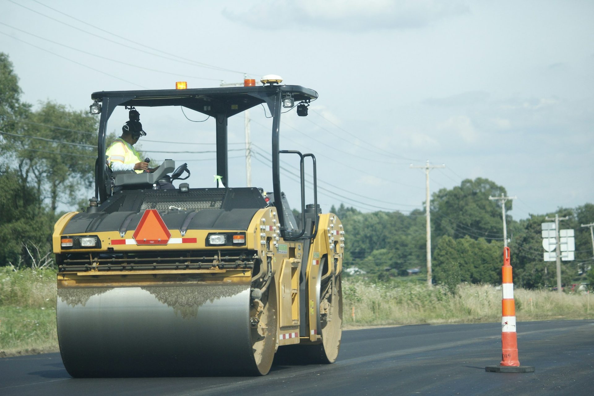 Roller compacting asphalt beside traffic cones