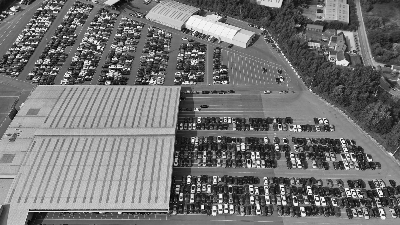 Aerial view of a commercial parking area and surrounding buildings.