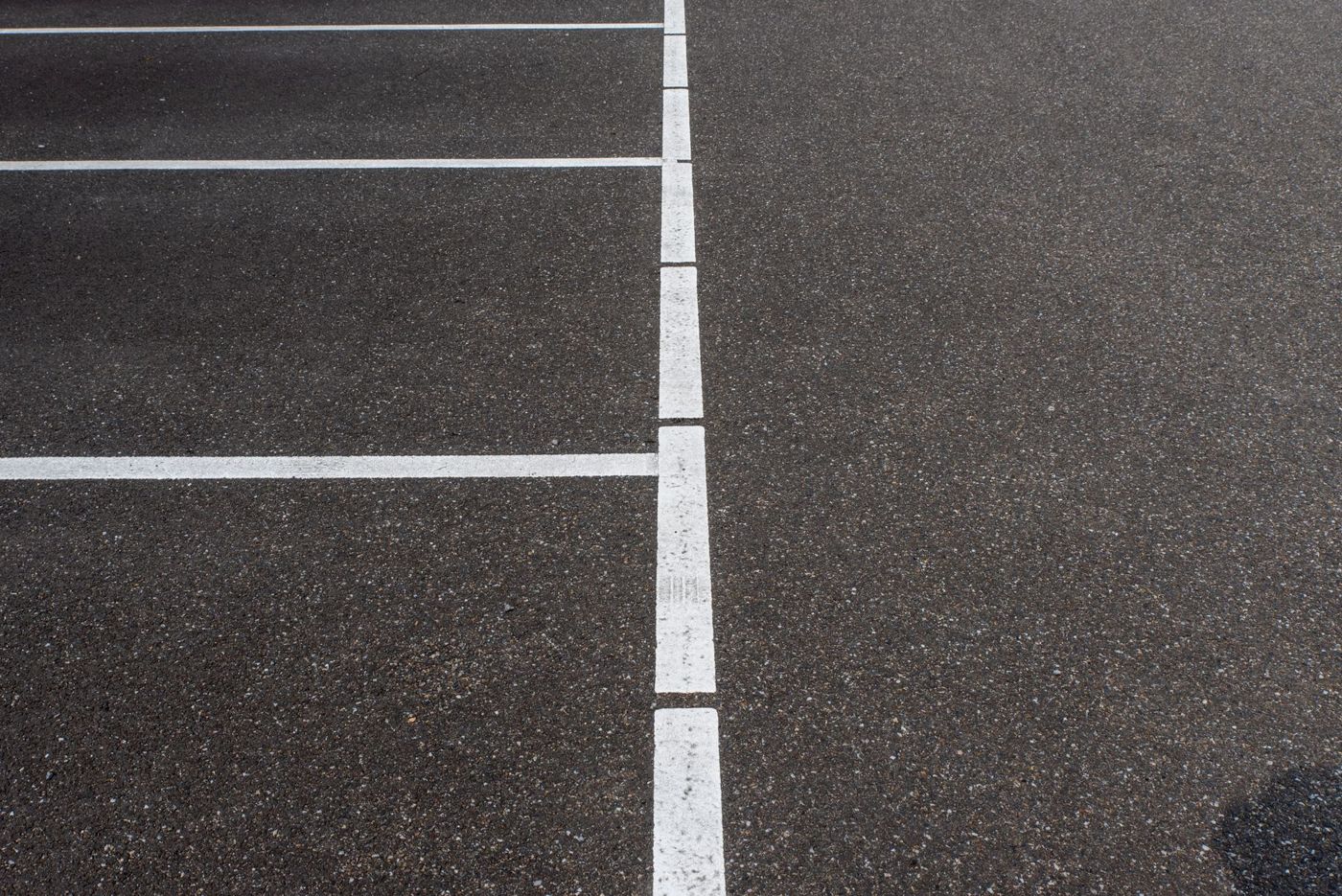 Dark asphalt parking surface with white parking lines.